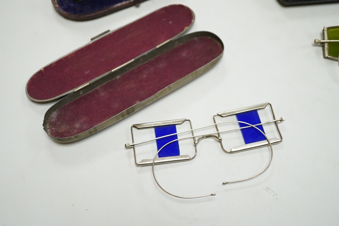Two pairs of 19th century double D folding tinted spectacles, both cased, an unusual pair of green tinted pince nez with vulcanite side eye protectors, cased and a pair of optometrist ‘patent’ spectacles with sliding blu